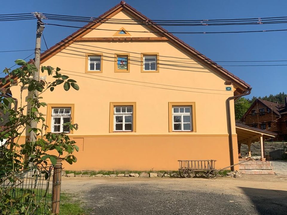 Průčelí zrekonstruované chalupy s dřevěným vozem